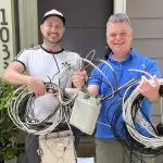 2 men hold telecom wires and a service box that Wire Free Sky removed from their home