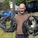 Older man holding coils of wires just removed from the exterior of his homs