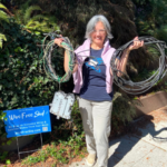 Photo of a woman happily holding up coils of telecom wire removed from her home