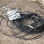 photo of coil of telecom wire and phone service box on dirt ground
