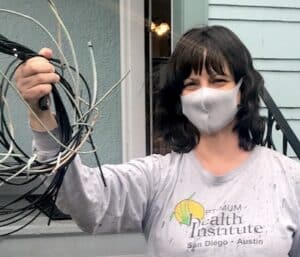 Woman wearing a Covid mask and holding up telecom wires Wire Free Sky removed from her home