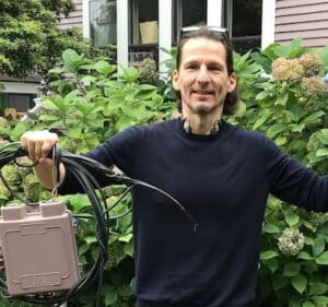 Man holding telecom wires and service boxes that Wire Free Sky removed from his home