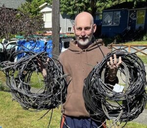 Older man holding coils of wires just removed from the exterior of his homs