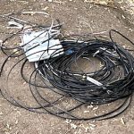 photo of coil of wire and phone service box on dirt ground