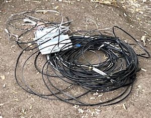photo of coil of telecom wire and phone service box on dirt ground