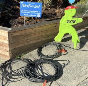 photo of coils of telecom wire on sidewalk, and florescent yellow person figure with text "slow down"