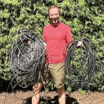 photo of a man hold many large coils of telecom wires that Wire Free Sky removed from his home