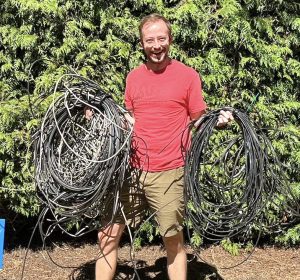 photo of a man hold many large coils of telecom wires that Wire Free Sky removed from his home