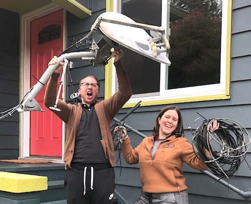 a victorious couple holding up a satellite dish and wires wire free sky removed