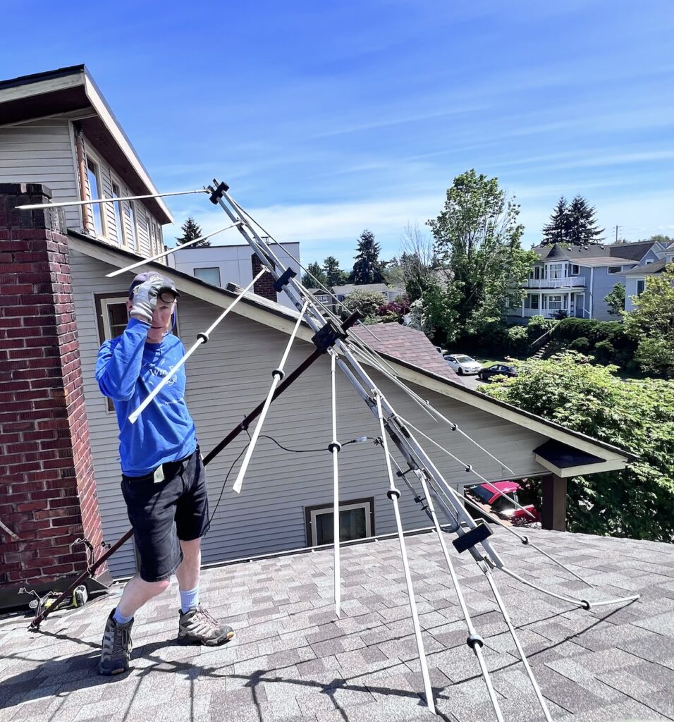 Man removing a TV antenna from a roof