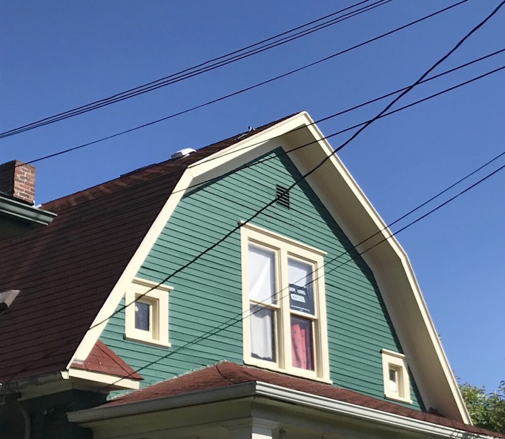 green dutch colonial house with many wires in the foreground